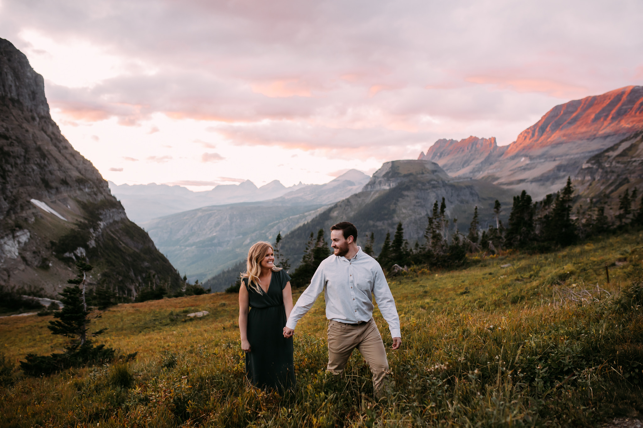 Couple walking through a feild surrounded by mountains